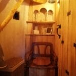 Hébergement Toilette sèche avec ancien siège d’aisance détourné, meuble étagère en bois et luminaire