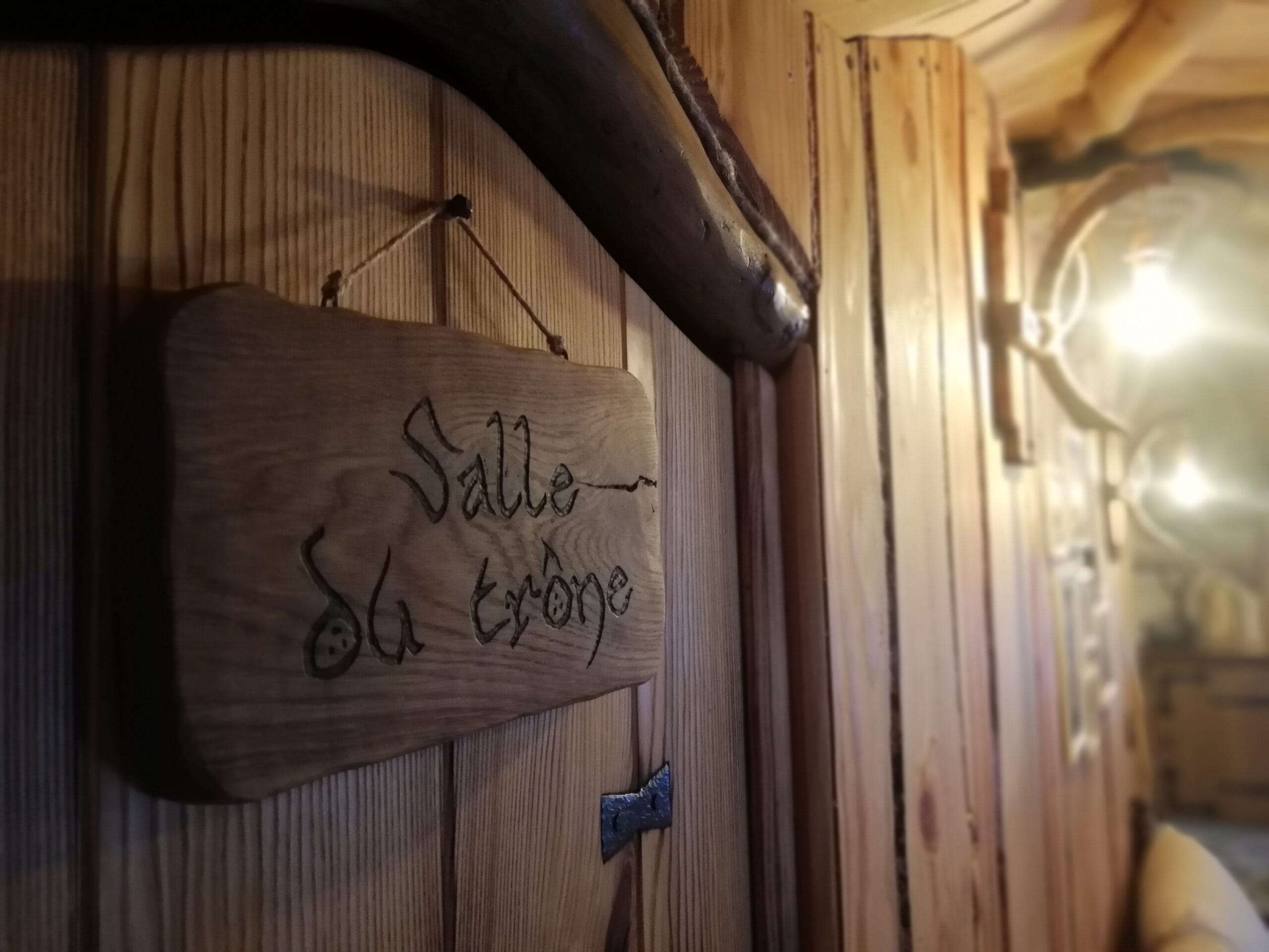 Hébergement Pancarte en bois gravée fixée sur une porte, luminaire flou en arrière-plan