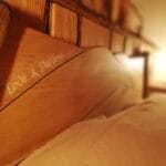 Hébergement Détail d’une gravure sur une tête de lit artisanale, luminaire flou en arrière-plan
