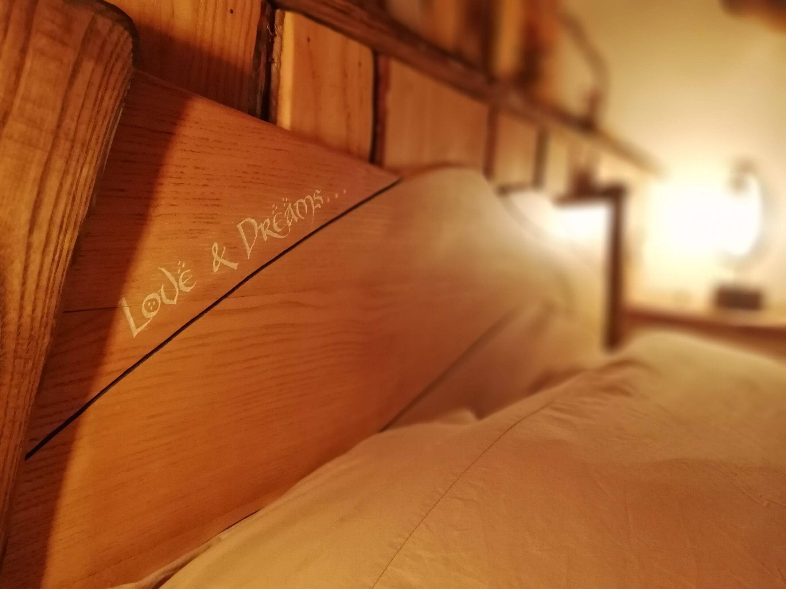 Hébergement Détail d’une gravure sur une tête de lit artisanale, luminaire flou en arrière-plan