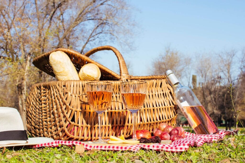 Panier de pique-nique posé sur l'herbe avec du pain, deux verres et une bouteille de vin