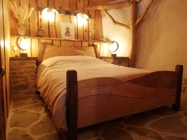 Lit artisanal féerique en bois avec luminaire et décorations en arrière-plan
